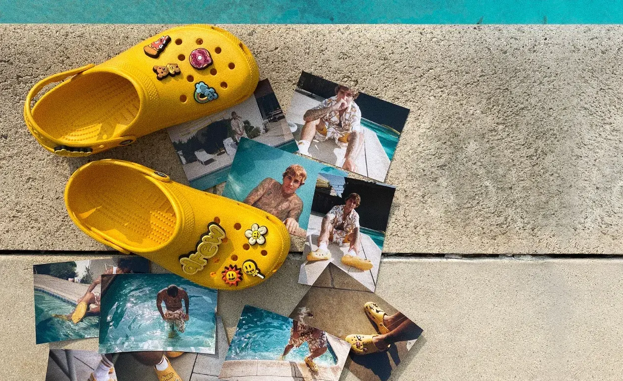 Justin Bieber x Crocs collaboration: Yellow Crocs on concrete with Bieber's photoshoot images.