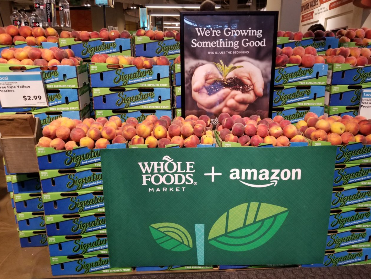 Peach crates with “Whole Foods + Amazon logo” and a "We're Growing Something Good" sign.