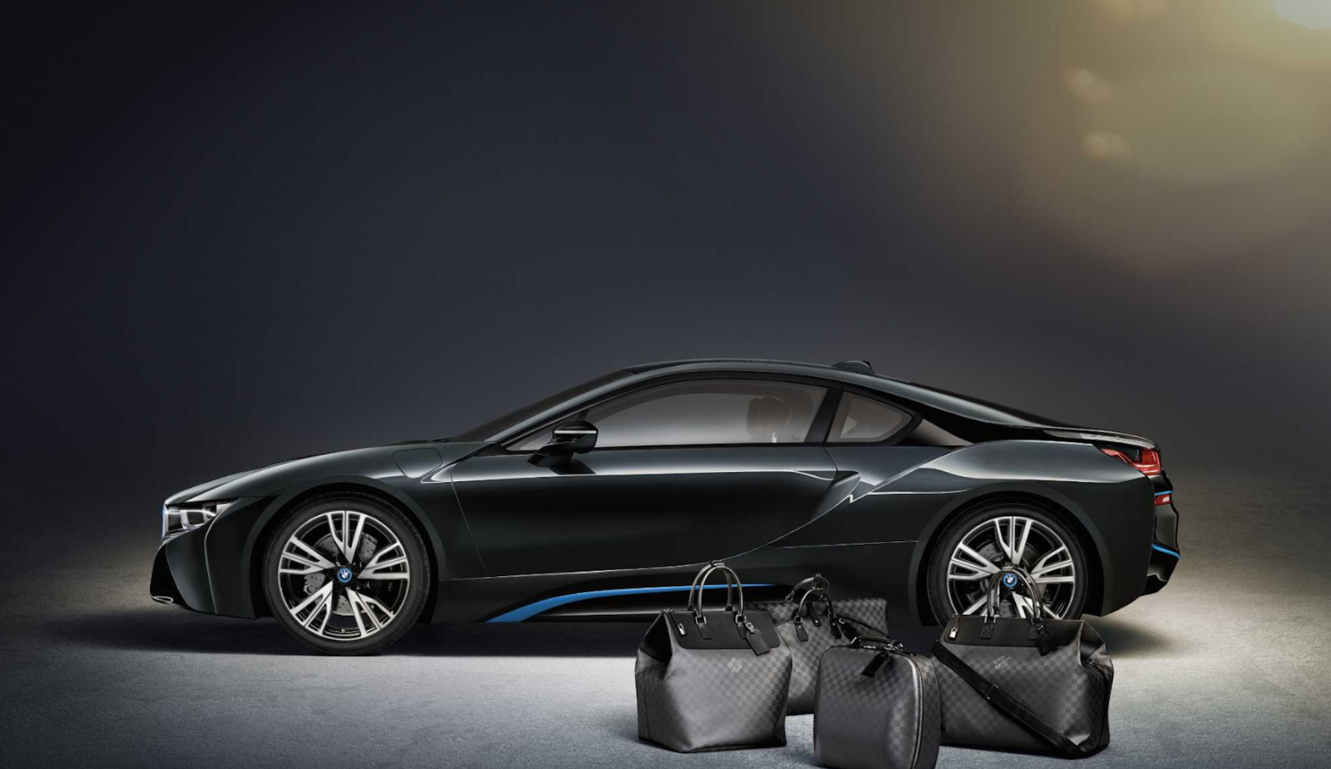 A black BMW i8 sports car with matching Louis Vuitton luggage