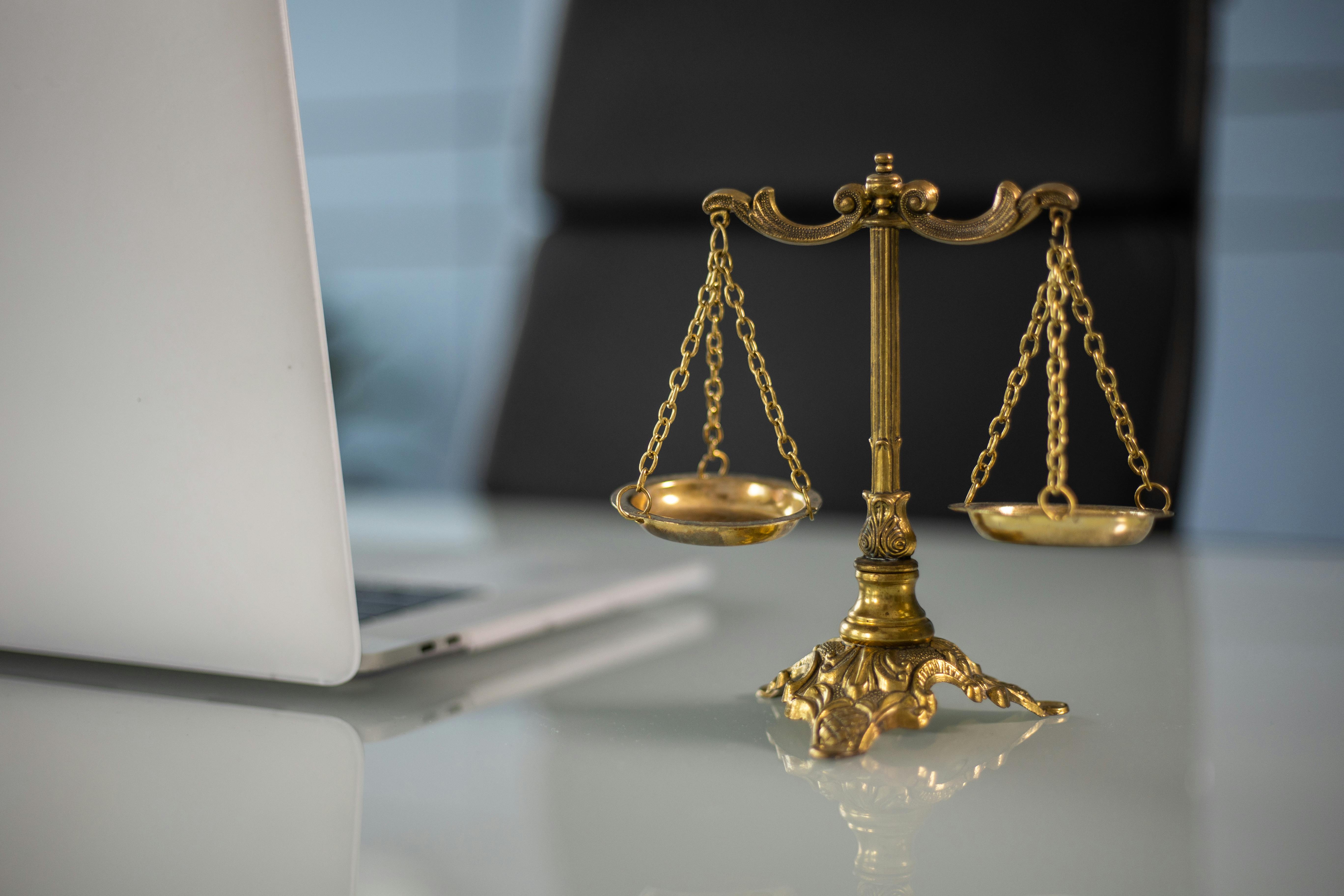 A balanced scale symbolizing legal compliance, placed on a table with books in the background