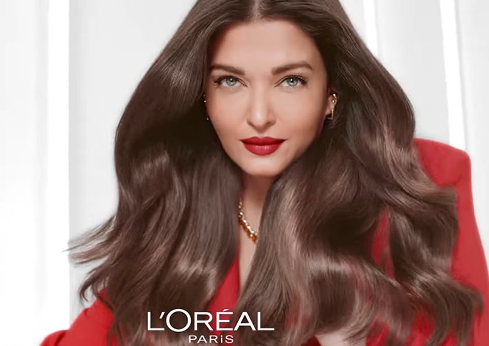 Image of Aishwarya Rai Bachcahn, Indian Actress, wearing a red blazer and red lipstick, posing for the L’Oreal Paris partnership campaign.